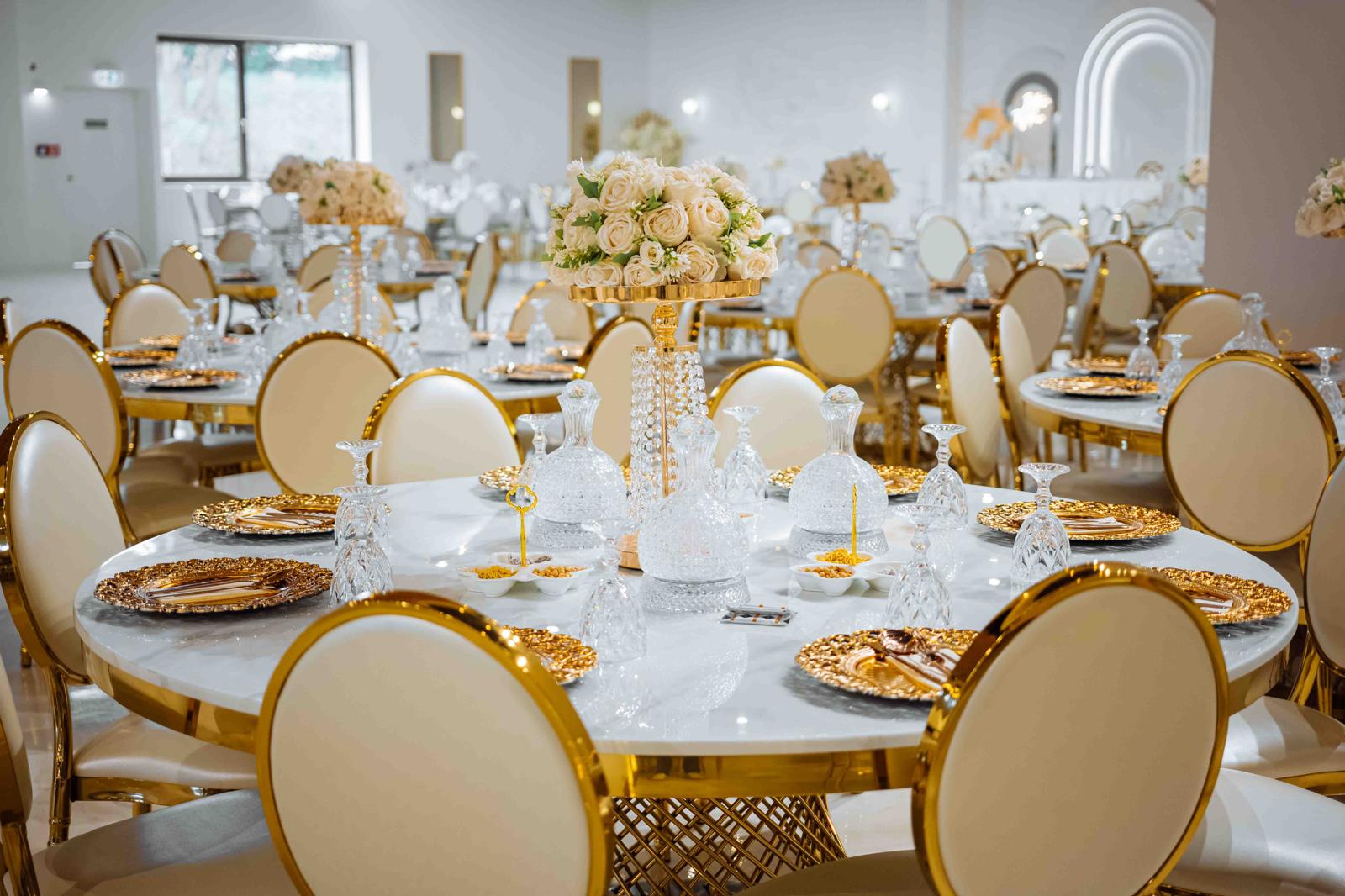 Weiße Rosen und Kristallvasen auf einer festlich gedeckten Hochzeitstafel